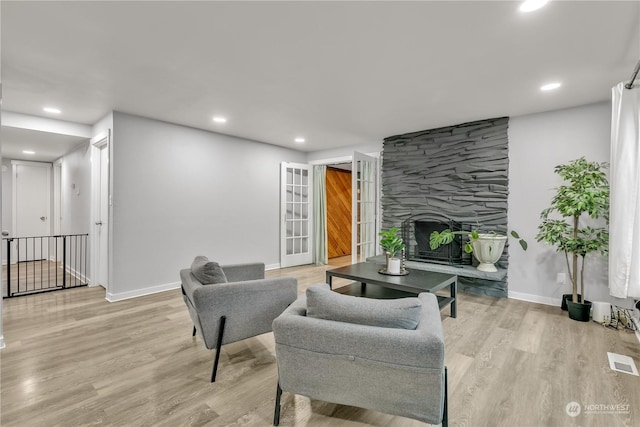 living room with a stone fireplace and light hardwood / wood-style floors