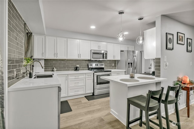 kitchen with white cabinets, pendant lighting, sink, and stainless steel appliances