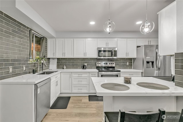 kitchen with light stone countertops, appliances with stainless steel finishes, sink, pendant lighting, and white cabinets