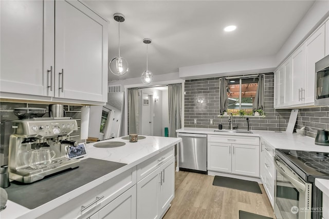 kitchen with sink, appliances with stainless steel finishes, tasteful backsplash, decorative light fixtures, and white cabinetry