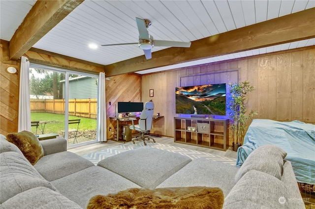 carpeted living room with beam ceiling, ceiling fan, and wooden walls