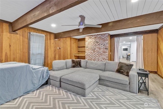 living room with beam ceiling, wooden walls, light hardwood / wood-style flooring, and ceiling fan