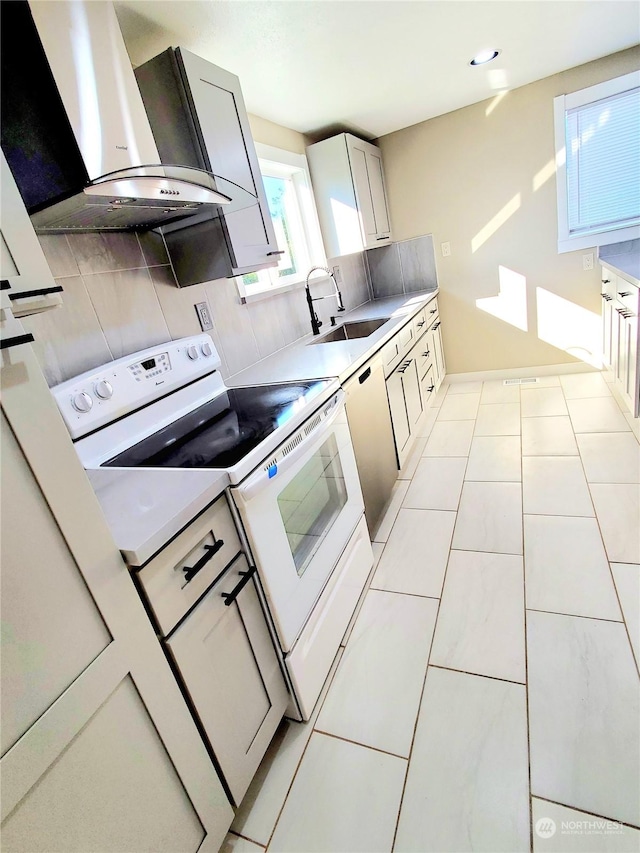 kitchen featuring tasteful backsplash, white appliances, wall chimney range hood, sink, and light tile patterned floors