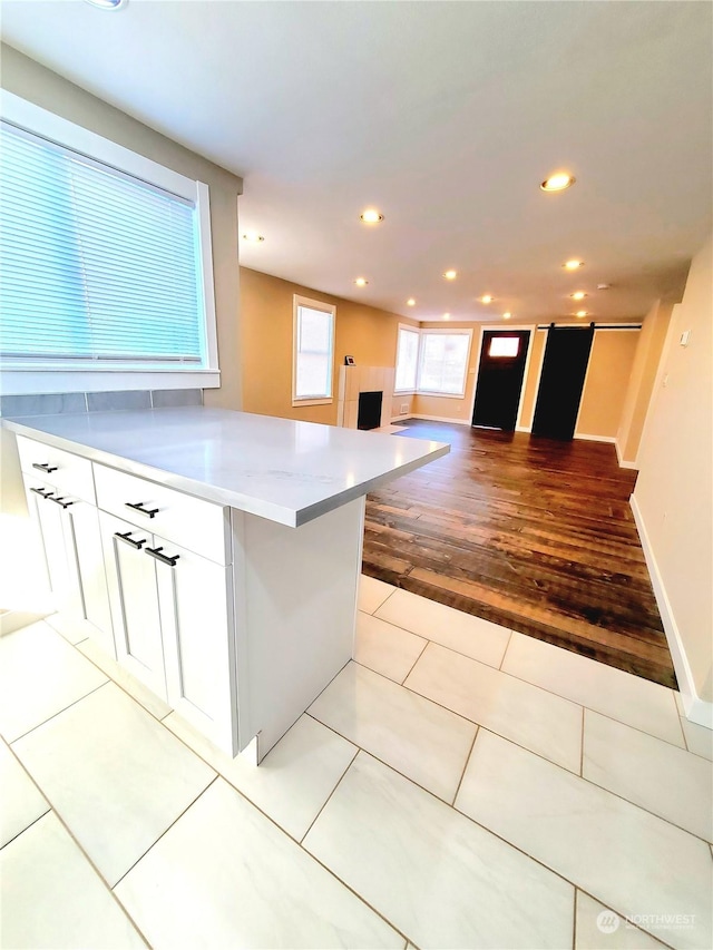 kitchen with kitchen peninsula, white cabinetry, and light tile patterned flooring