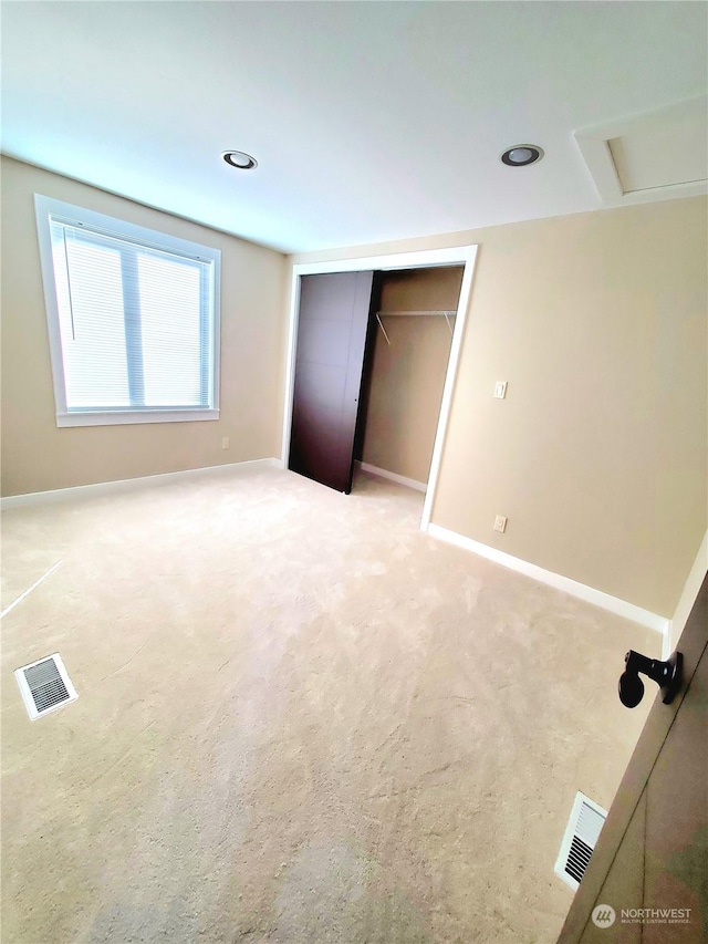 unfurnished bedroom featuring light carpet and a closet