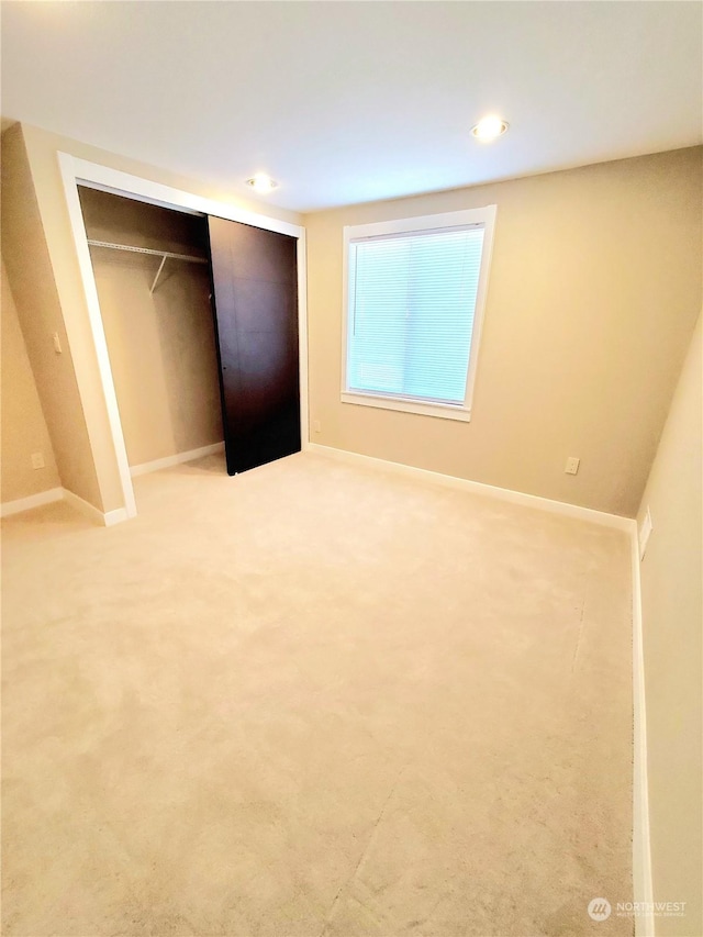 unfurnished bedroom featuring light colored carpet and a closet