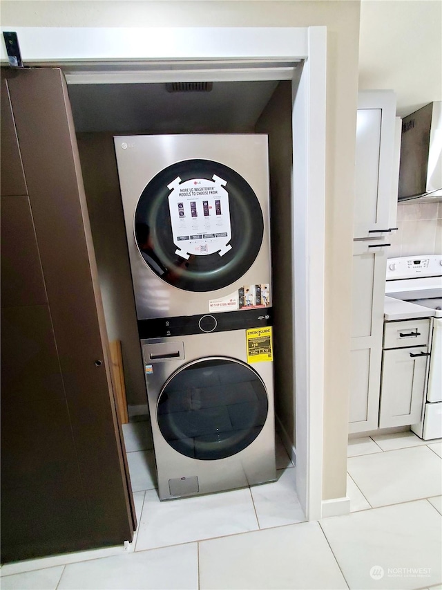 laundry area with light tile patterned floors and stacked washer / drying machine