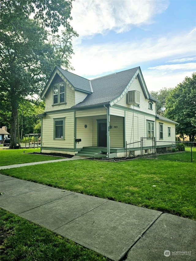 view of front of home with a front yard, fence, and a shingled roof