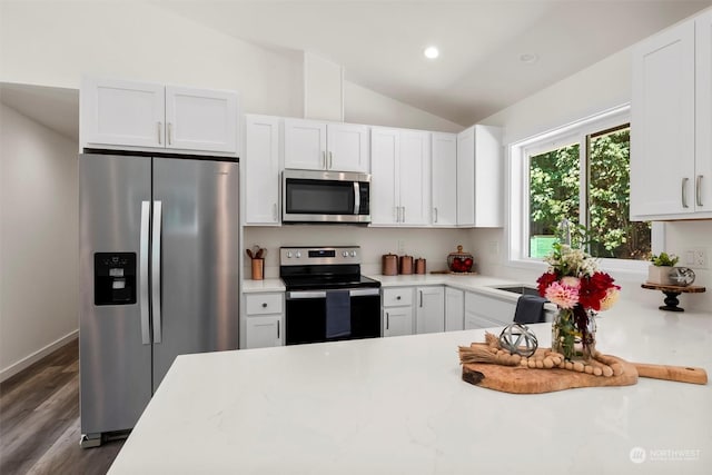 kitchen with white cabinetry, appliances with stainless steel finishes, dark hardwood / wood-style floors, and vaulted ceiling