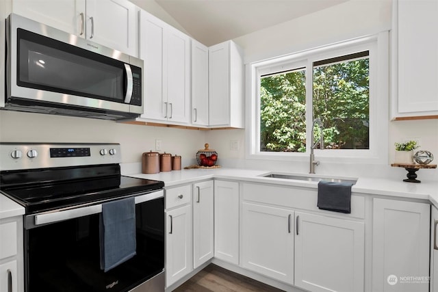 kitchen with lofted ceiling, sink, hardwood / wood-style flooring, stainless steel appliances, and white cabinets