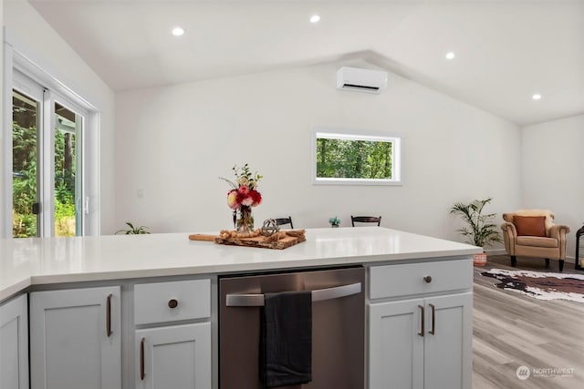 kitchen with stainless steel dishwasher, a wall mounted AC, vaulted ceiling, and a wealth of natural light