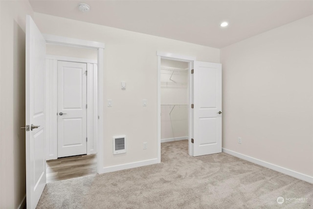 unfurnished bedroom with light carpet, a spacious closet, and a closet