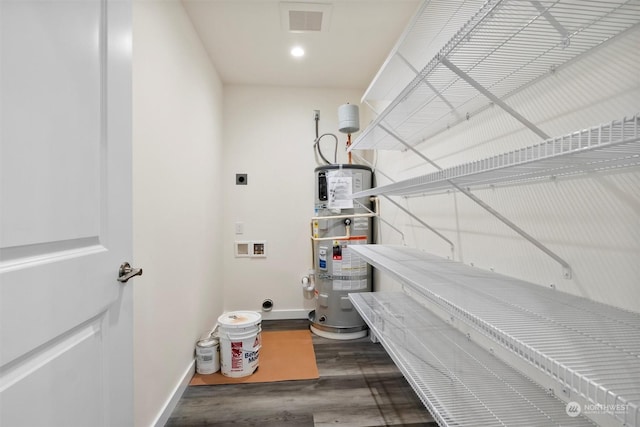 interior space featuring water heater, hookup for a washing machine, dark wood-type flooring, and hookup for an electric dryer