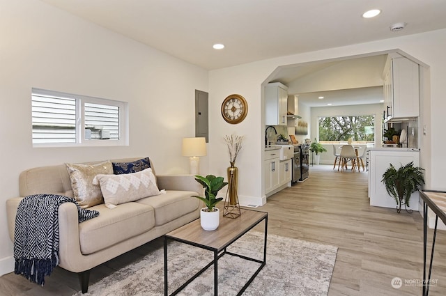 living room with light hardwood / wood-style floors, sink, and electric panel