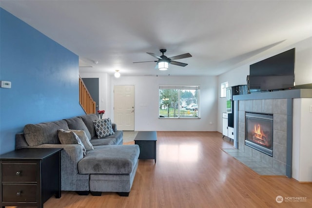 living room with a fireplace, light hardwood / wood-style flooring, and ceiling fan