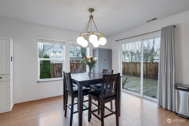 dining space featuring a healthy amount of sunlight, light hardwood / wood-style flooring, and an inviting chandelier