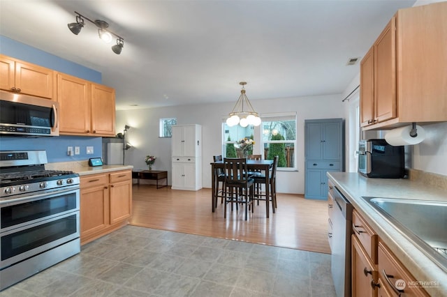 kitchen with pendant lighting, light brown cabinets, stainless steel appliances, and sink