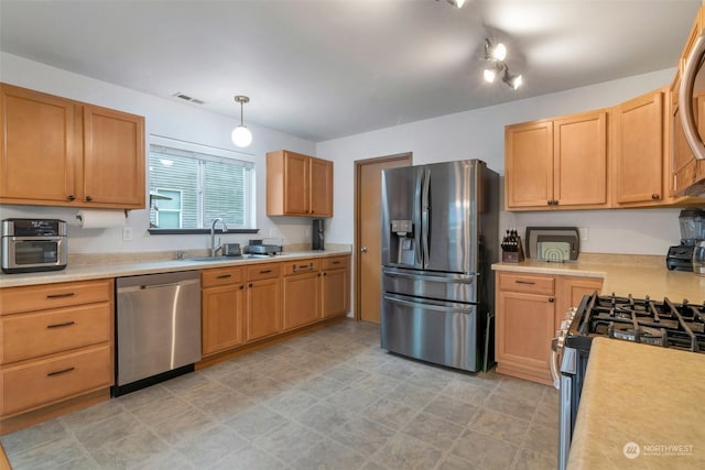 kitchen featuring appliances with stainless steel finishes, decorative light fixtures, and sink