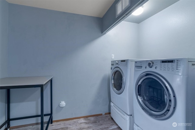 laundry area featuring separate washer and dryer and light hardwood / wood-style flooring