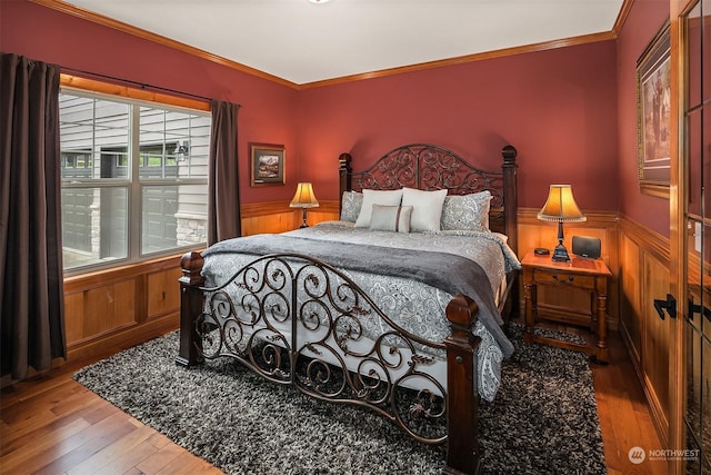 bedroom with hardwood / wood-style flooring, ornamental molding, and wooden walls