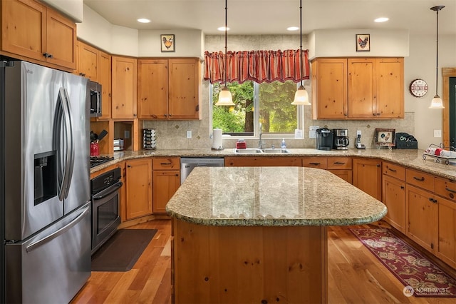 kitchen featuring stainless steel appliances, sink, decorative light fixtures, light hardwood / wood-style floors, and decorative backsplash