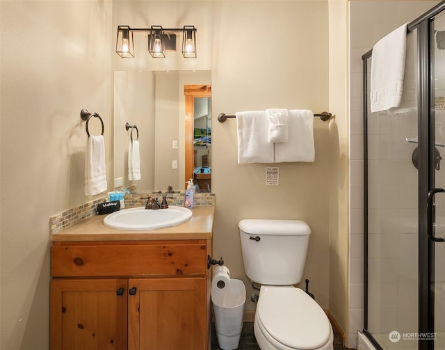 bathroom with toilet, walk in shower, vanity, and backsplash