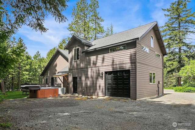 view of property exterior with a hot tub, central AC unit, and a garage