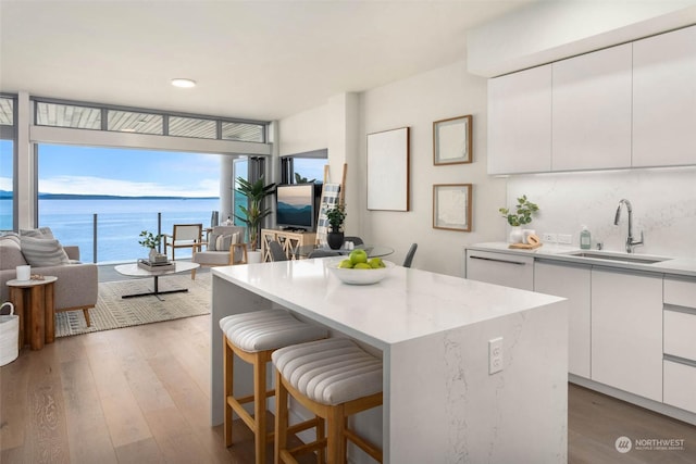 kitchen featuring a water view, sink, white cabinetry, a kitchen island, and wood-type flooring