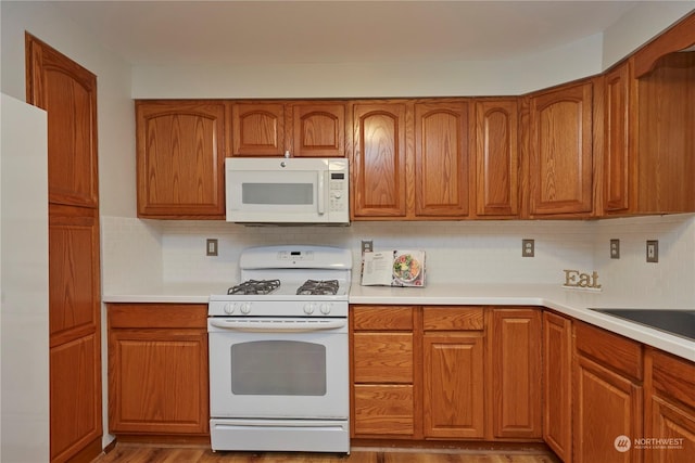 kitchen featuring light hardwood / wood-style floors, white appliances, and backsplash