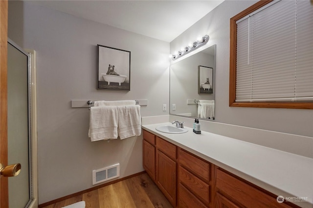 bathroom featuring vanity, wood-type flooring, and walk in shower