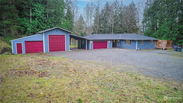 single story home featuring a detached garage and gravel driveway