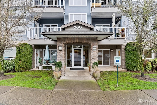 doorway to property with a balcony and a yard