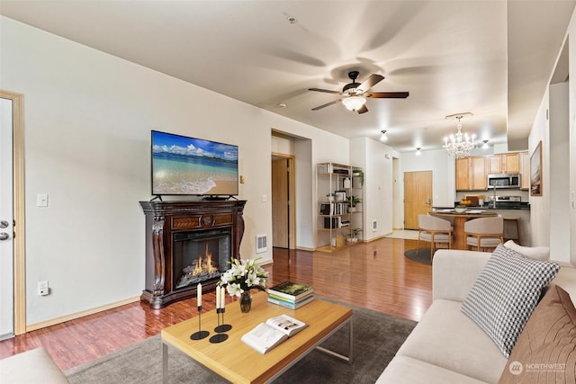 living room with ceiling fan with notable chandelier and hardwood / wood-style floors