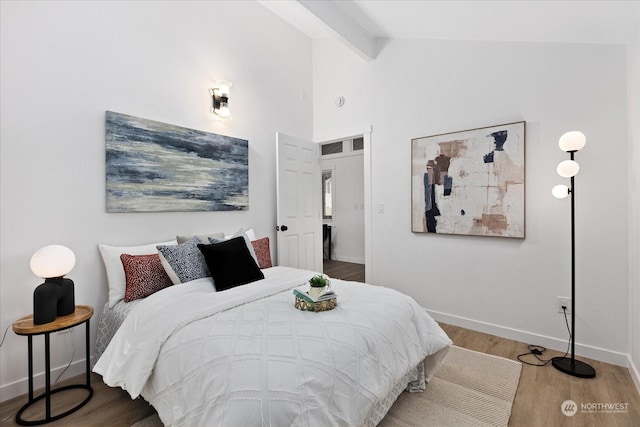 bedroom with vaulted ceiling with beams and light wood-type flooring