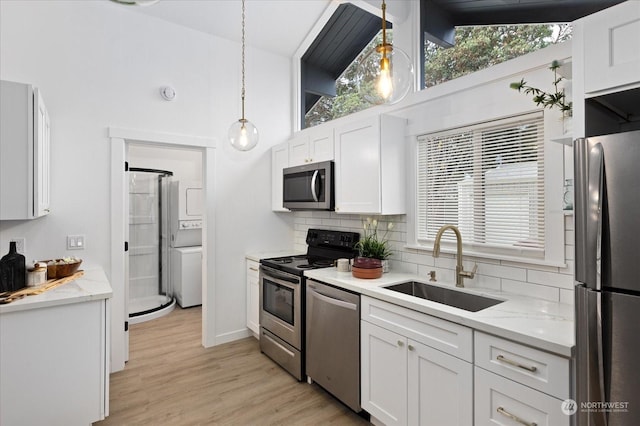 kitchen featuring high vaulted ceiling, sink, appliances with stainless steel finishes, decorative light fixtures, and white cabinetry