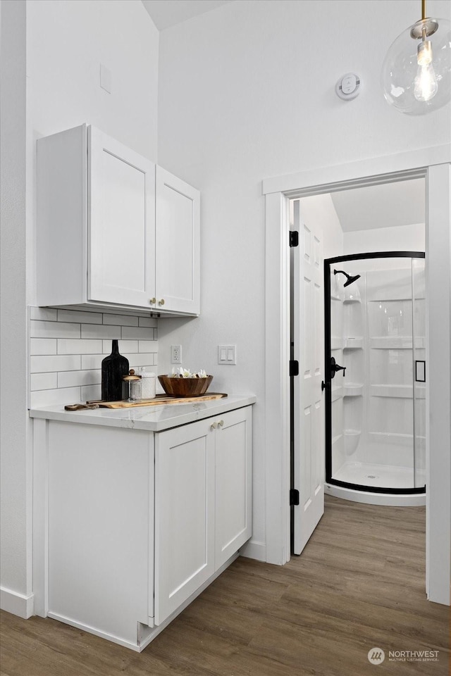 bar featuring tasteful backsplash, white cabinets, hanging light fixtures, and dark hardwood / wood-style floors