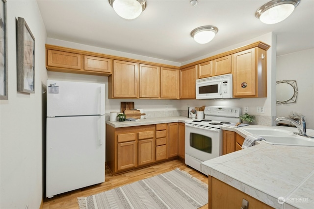 kitchen featuring tile countertops, white appliances, sink, light hardwood / wood-style flooring, and kitchen peninsula