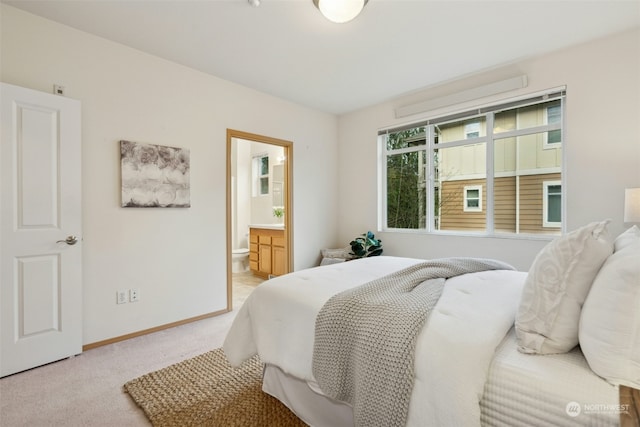 bedroom with connected bathroom and light colored carpet