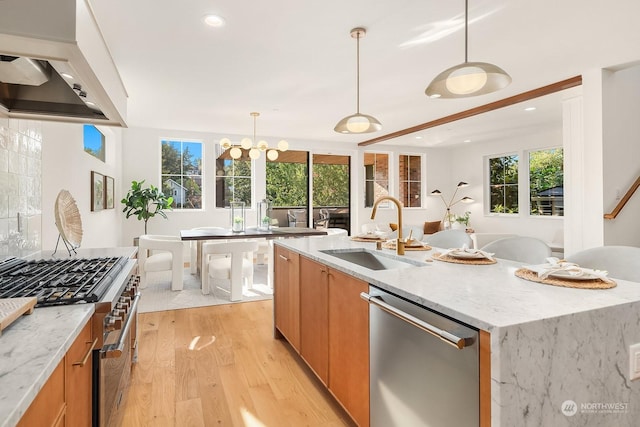 kitchen featuring decorative light fixtures, sink, light stone counters, and stainless steel appliances