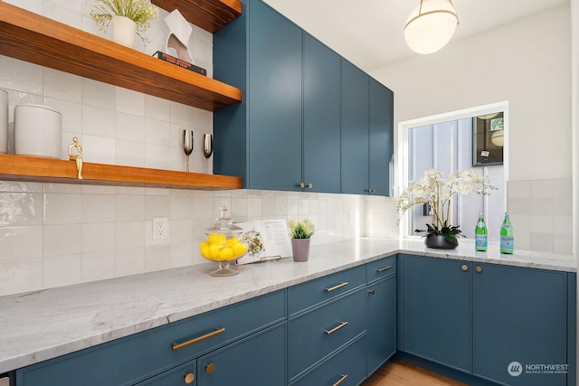 kitchen with tasteful backsplash, light stone counters, and blue cabinets