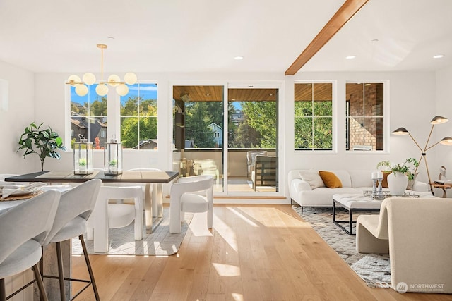 dining area with beam ceiling, light hardwood / wood-style floors, and an inviting chandelier