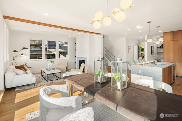 dining area with hardwood / wood-style floors, sink, beamed ceiling, and a chandelier