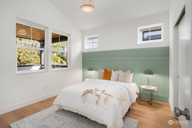 bedroom with light wood-type flooring and lofted ceiling