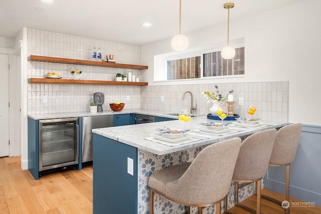 kitchen featuring sink, hanging light fixtures, wine cooler, kitchen peninsula, and a kitchen bar