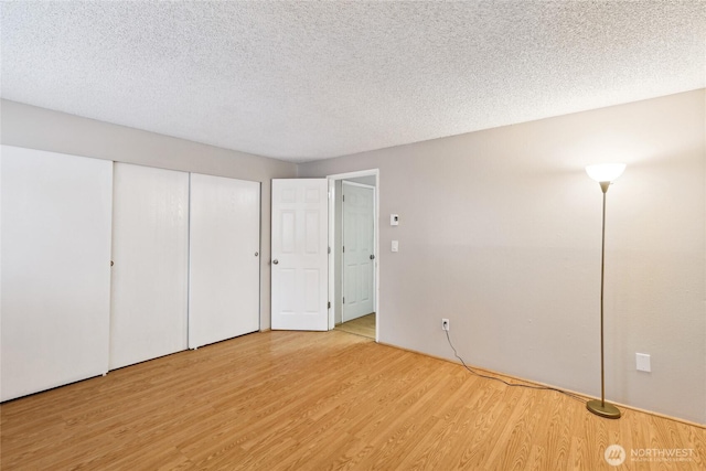 unfurnished bedroom featuring a closet, a textured ceiling, and light wood-type flooring