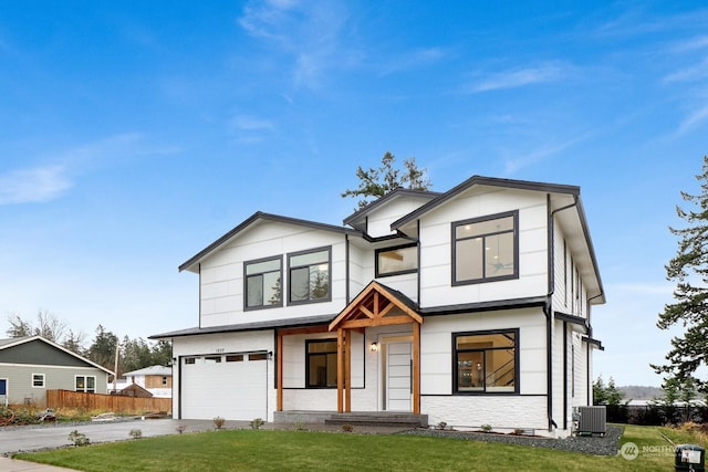 view of front of property featuring a front yard, a garage, and central AC unit