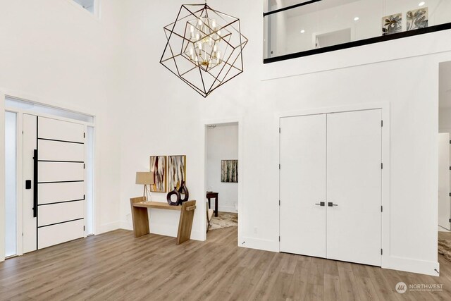 entryway with a towering ceiling, hardwood / wood-style flooring, and an inviting chandelier