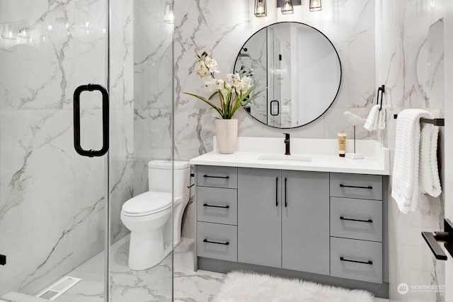 bathroom with vanity, toilet, a shower with door, and tile walls