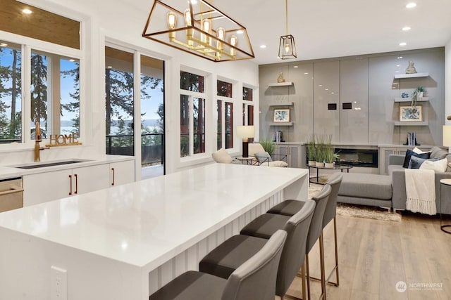 kitchen with a kitchen bar, sink, pendant lighting, and light hardwood / wood-style flooring