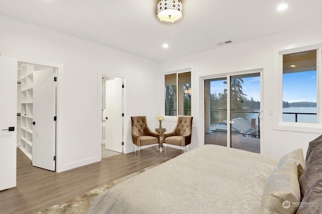 bedroom with access to exterior, a water view, and hardwood / wood-style floors